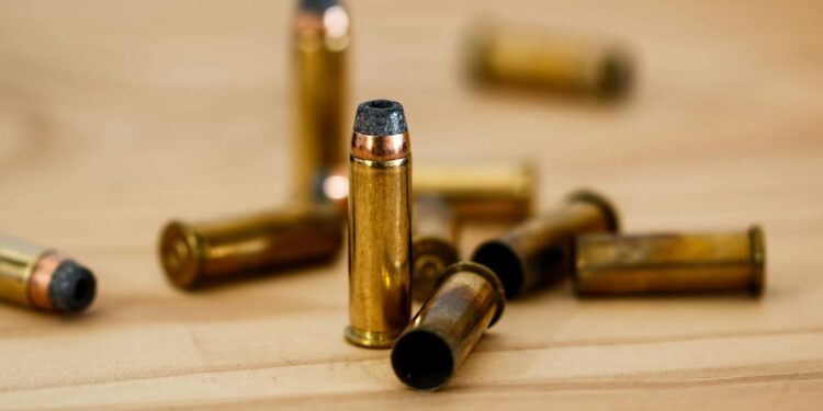 Detailed view of brass bullet shells scattered on a wood background.