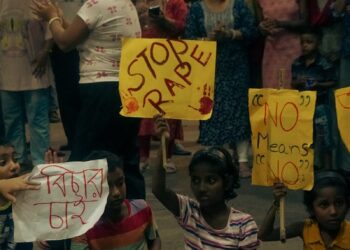 A group of people gather for a protest advocating women's safety at night.