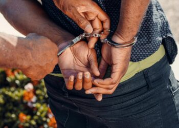 Close-up of a police officer handcuffing a man outdoors. Law enforcement in action.