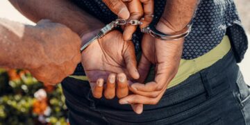Close-up of a police officer handcuffing a man outdoors. Law enforcement in action.