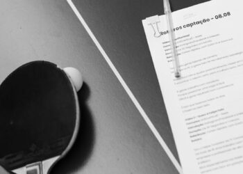 Black and white photo of a table tennis racket and a document on a table, featuring copyspace.